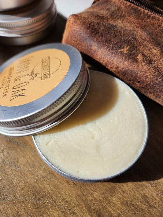 Balm tin with open lid on a wooden surface, showing a leather pouch and additional tins.