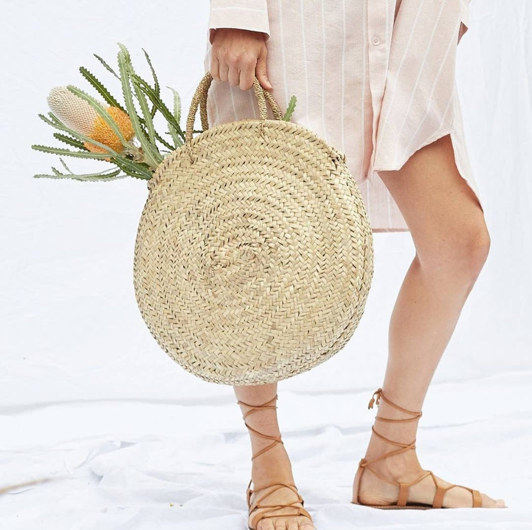 round basket with flowers in front of women with strappy sandals